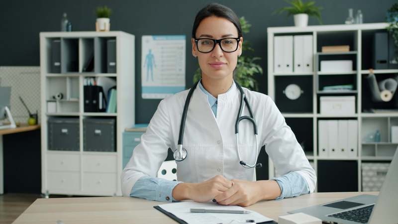 Female healthcare administrator reviewing digital health records on laptop in modern office